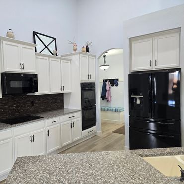 Modern kitchen with white cabinets and black appliances.