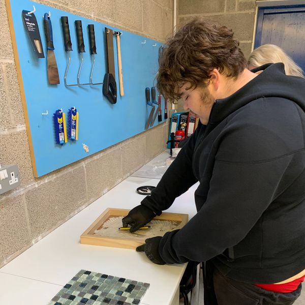 Young man grouting tiles in a workshop.