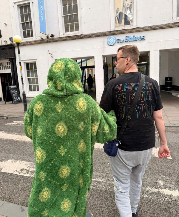 Two people walking, one in a green patterned coat.
