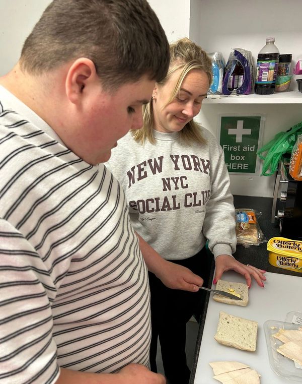 Two people preparing sandwiches in a kitchen.