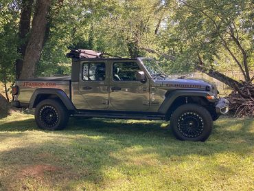 Jeep Gladiator parked on grass by trees and water.