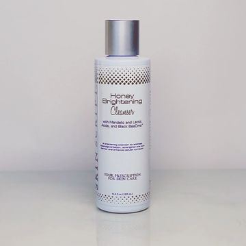 Bottle of Honey Brightening Cleanser on a plain surface.
