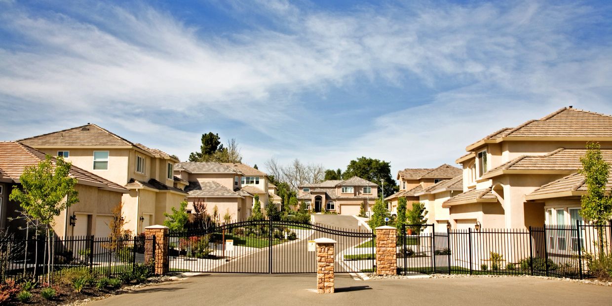 Gated suburban neighborhood with modern houses and clear skies.