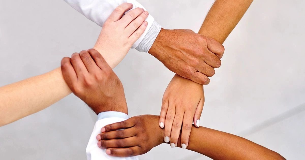 Four diverse hands joined in unity.