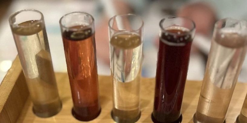 Five test tubes with different colored liquids in a wooden rack.