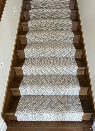 Wooden stairs with a patterned beige carpet runner.