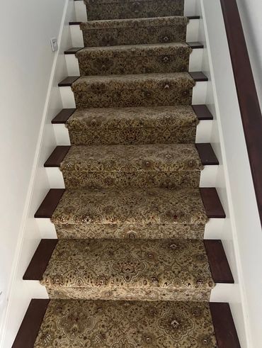 Carpeted stairs with an intricate floral pattern and wooden accents.