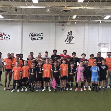 Youth soccer team posing indoors in colorful uniforms.