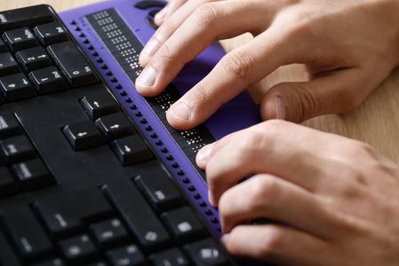 Image of a blind individual using a Braille keyboard.