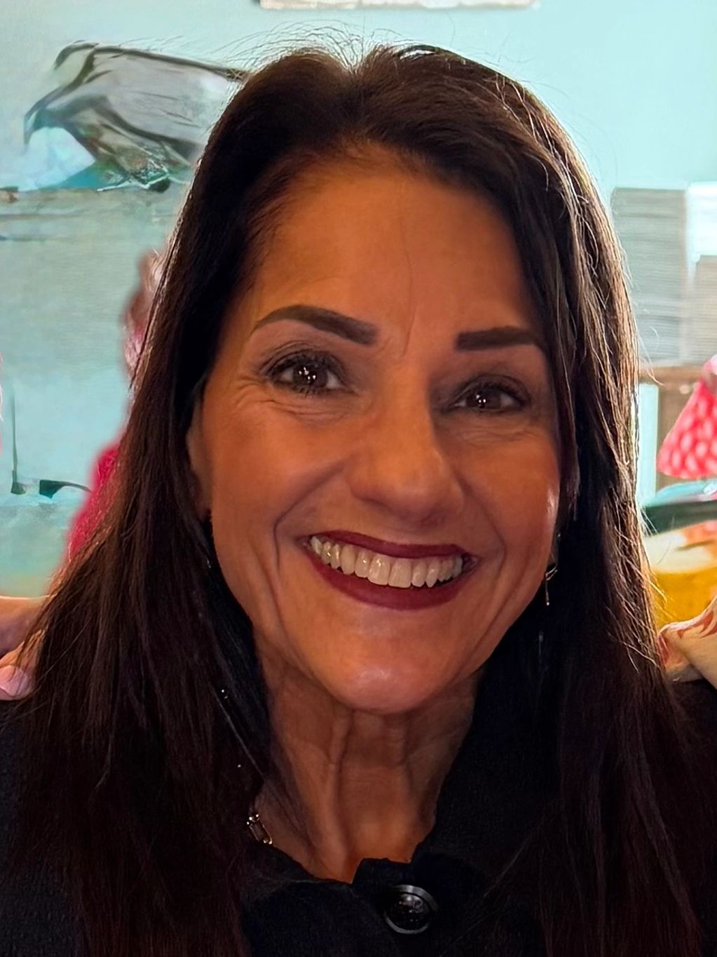 Smiling woman with dark hair and expressive eyes.