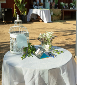 Decorative table setup with flowers and a birdcage at an outdoor event.