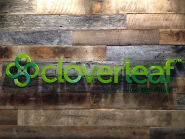 Acrylic stud mount lobby sign installed onto wood wall.