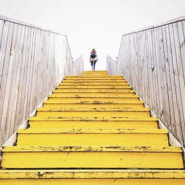 a woman climbing the yellow color stairs 