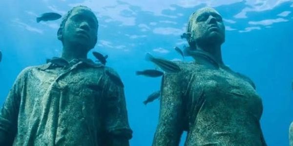 Underwater statues with fish swimming around.