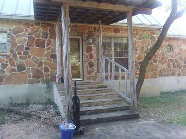 Stone house entrance with rustic wooden porch and steps.