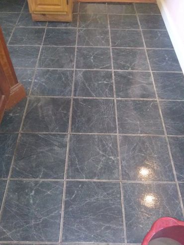 Dark gray marble floor tiles with white veins in a kitchen area.