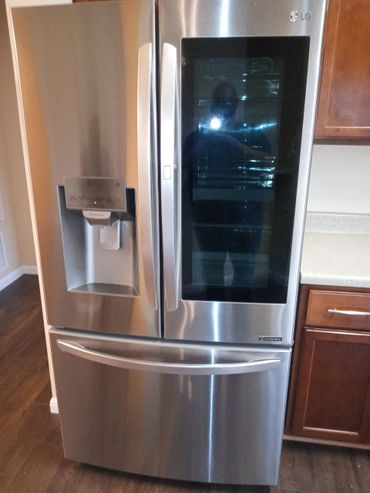 Stainless steel LG refrigerator with a glass door and water dispenser.