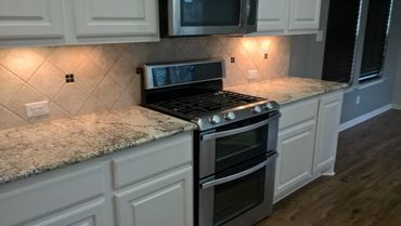 Modern kitchen with granite countertops and stainless steel stove.
