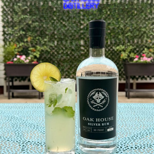 Bottle of Oak House Silver Rum and a cocktail with lime garnish.