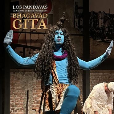 Actor painted blue performing a dramatic pose in a theatrical production.