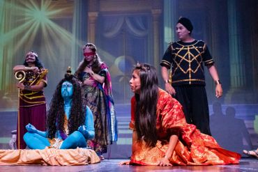 Actors in colorful costumes performing a dramatic stage play.
