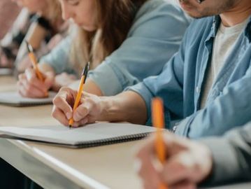 Students writing notes in notebooks during a class.