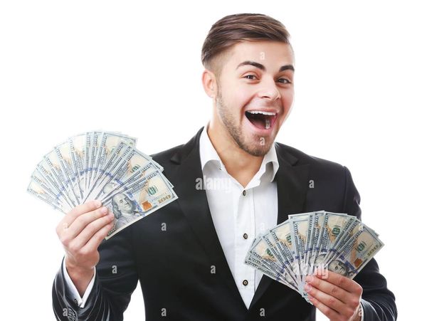 Excited man in suit holding large amounts of money in both hands.
