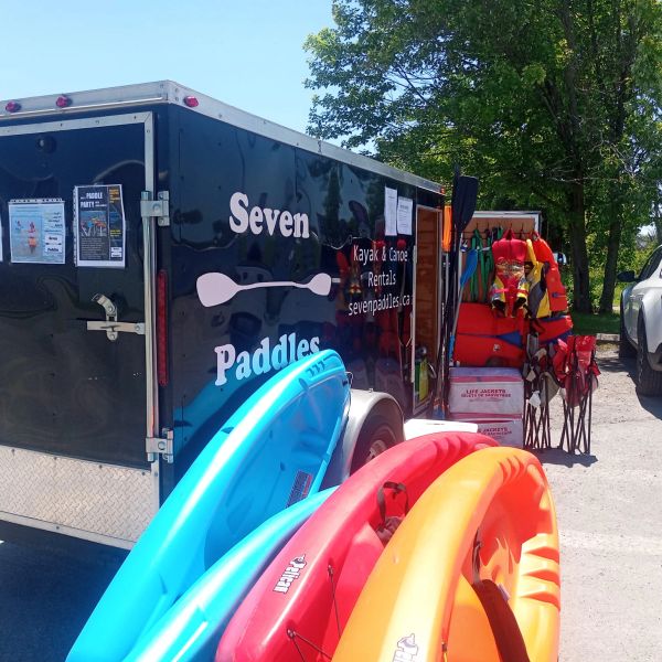 Kayak rental trailer with colorful kayaks and life jackets.