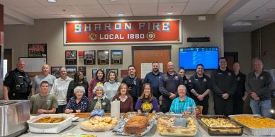 Group photo of firefighters and community members with a feast at Sharon Fire Local 1880.