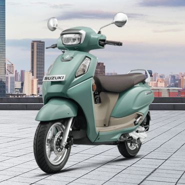 A mint green Suzuki scooter parked on a city rooftop with skyline in the background.