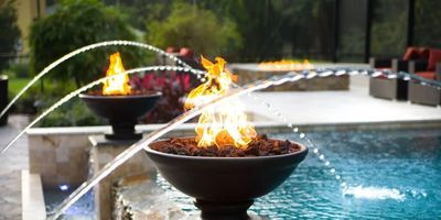 Decorative fire bowls with water jets around a pool.