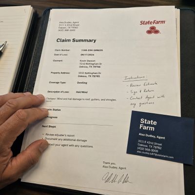State Farm claim summary document and business card on a desk.