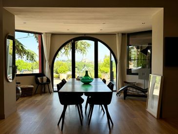 Modern dining room with large arched window and wooden floors.