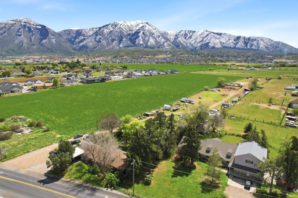 Scenic farmland with houses and snow-capped mountains in the background.