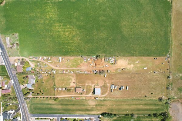 Aerial view of a rural farm with green fields and scattered buildings.
