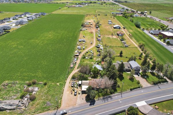 A rural area with houses, dirt paths, and green fields under clear skies.
