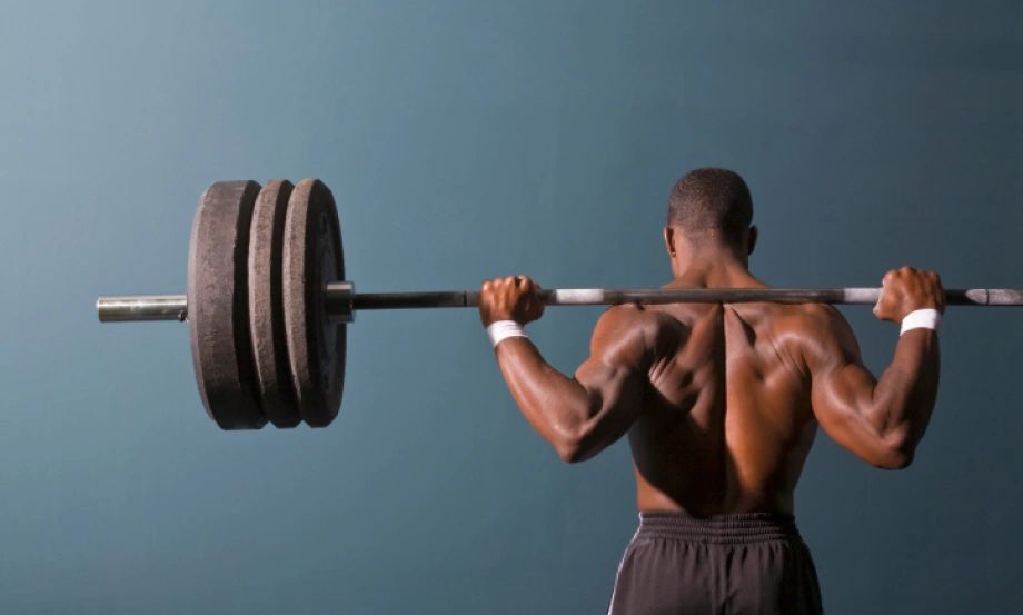 a man holding gym weights over his shoulders