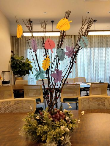 Decorative centerpiece with branches and colorful paper leaves featuring positive words.