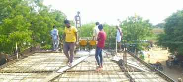 Workers pouring concrete on a rooftop construction site.