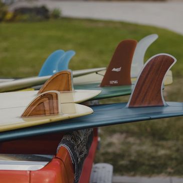 A bunch of beautiful hand shaped surfboards hanging of the back of a pick up truck getting ready for