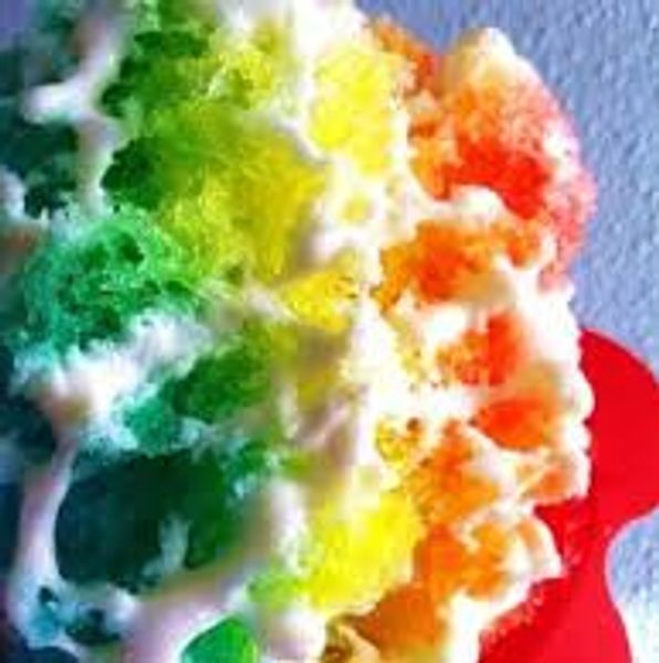 Close-up of a colorful rainbow snow cone with white syrup drizzle.