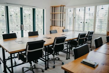 Modern conference room with wooden tables and black office chairs.