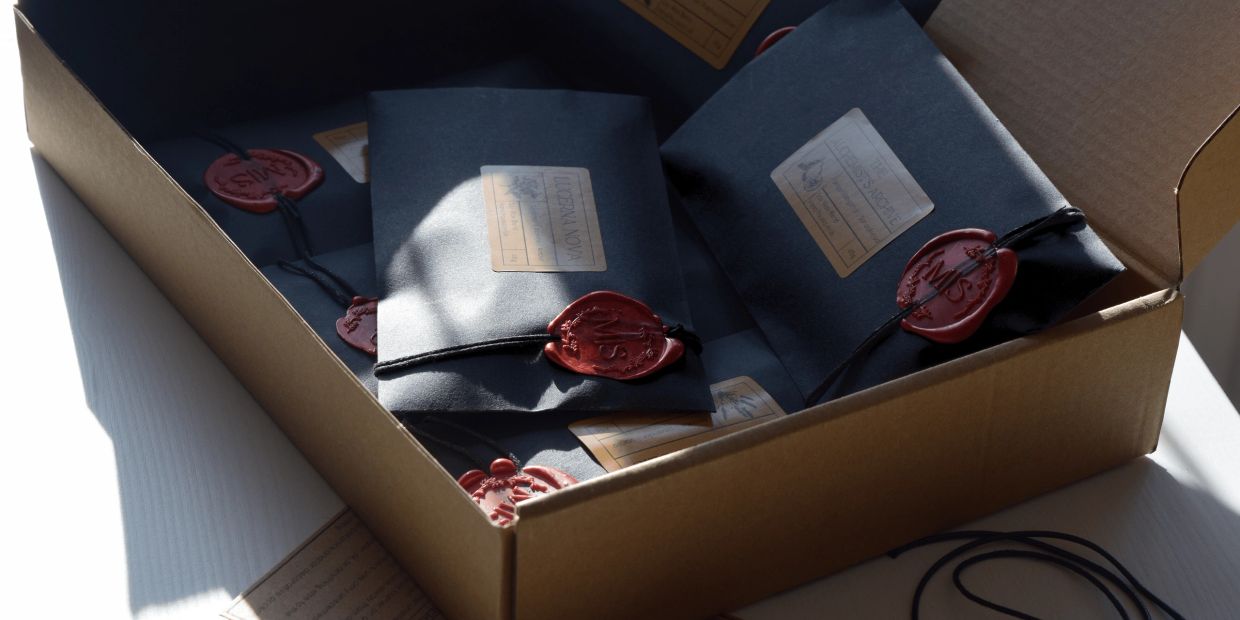 Box filled with black envelopes sealed with red wax stamps.
