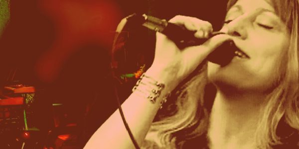 Woman passionately singing into a microphone on stage.