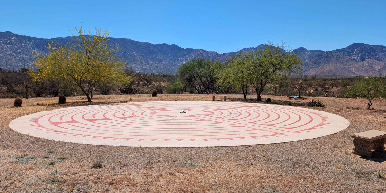 Outdoor circular labyrinth under sunny blue sky.