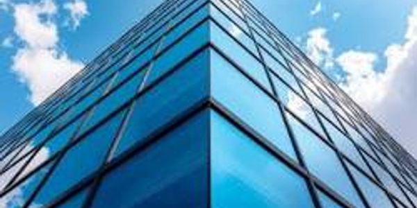 Looking up at a modern glass skyscraper reflecting the sky.