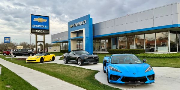Chevrolet dealership with vibrant sports cars displayed outside on a cloudy day.