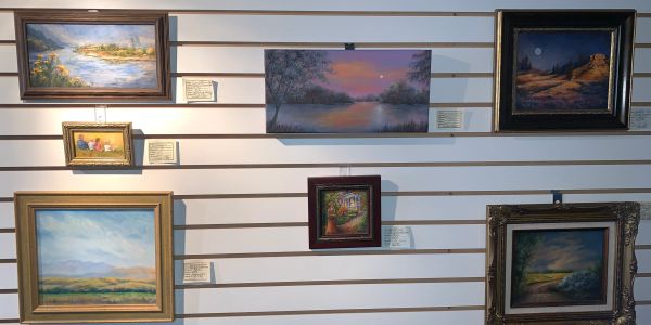Gallery wall displaying various framed landscape paintings.
