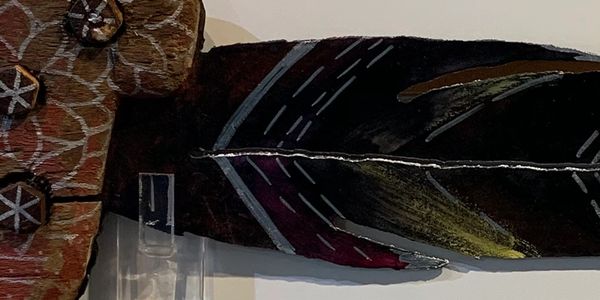 Close-up of a painted feather and textured wooden object.