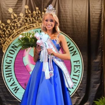 Smiling beauty queen in a blue gown with crown and flowers.